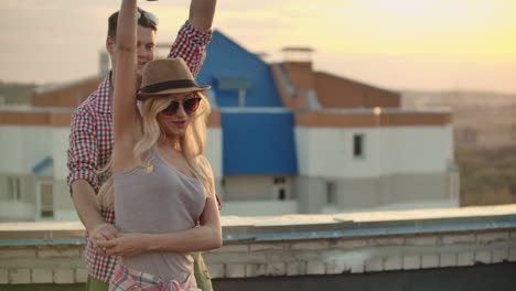 Loving-couple-in-red-plaid-shirts-move-in-dance-on-the-roof.-Girl-with-beer-spinning-in-dance-with-her-russian-boyfriend.-She-moves-her-body-beautifully